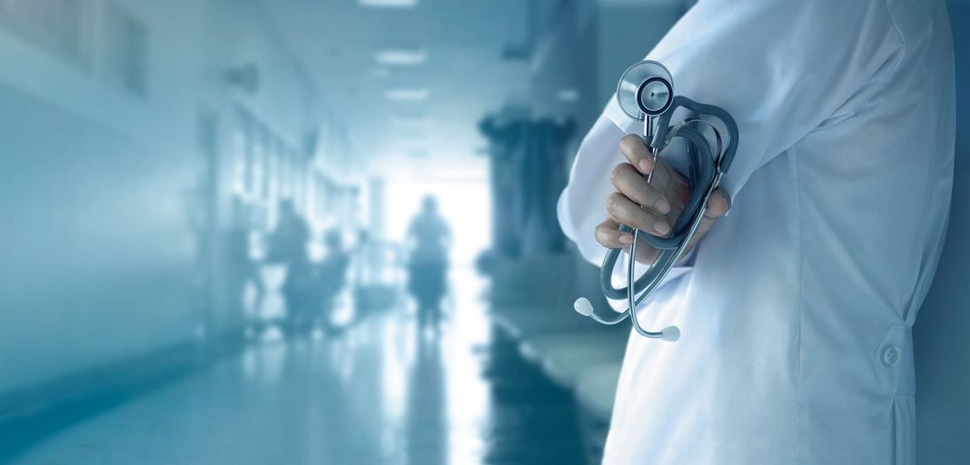 Doctor with stethoscope in hand on hospital background